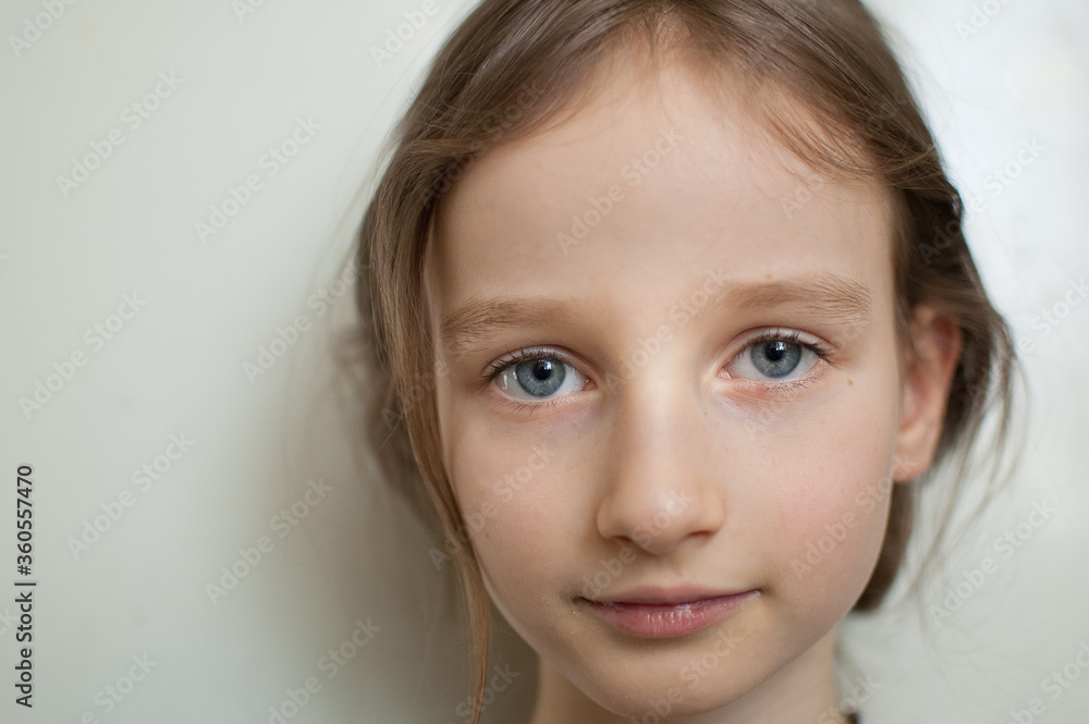 Portrait of a little girl with long blond hair and blue eyes with ponytail is standing on white background in studio Portrait of a little girl with long blond hair and blue eyes with ponytail is standing on white background in studio