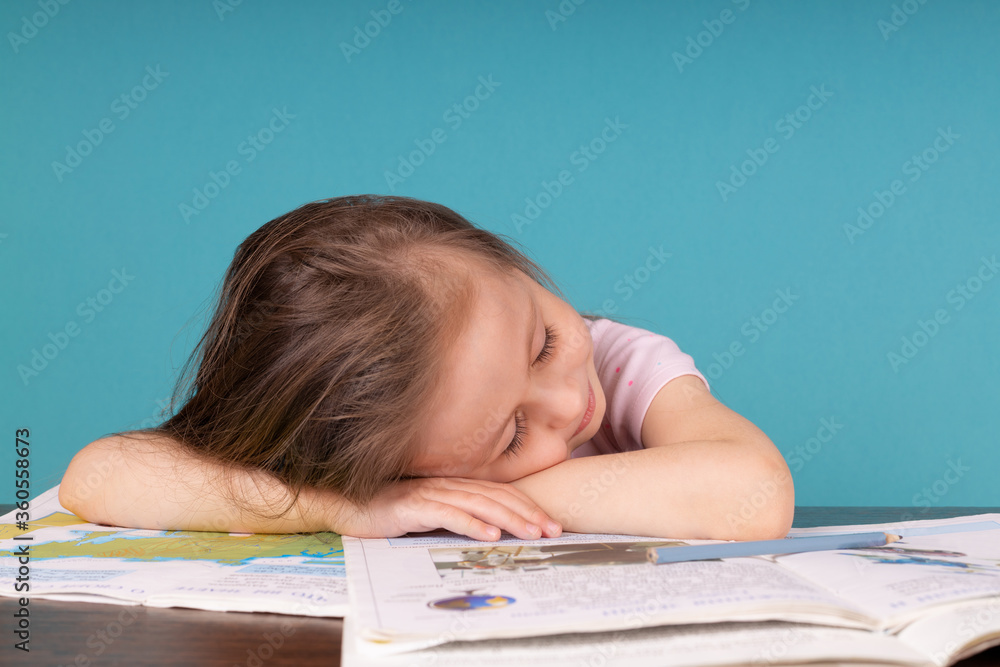 Little girl fell asleep on the table on books when doing homework Little girl fell asleep on the table on books when doing homework