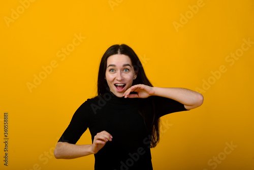 Wow. Beautiful female front portrait isolated on yellow studio backgroud. Young emotional surprised woman standing with open mouth. Human emotions, facial expression concept. © Ivan Zelenin