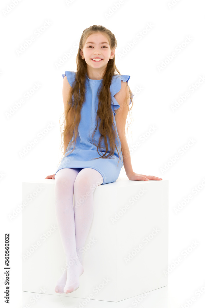 Little girl poses for a magazine in the studio on a white cube. Little girl poses for a magazine in the studio on a white cube.