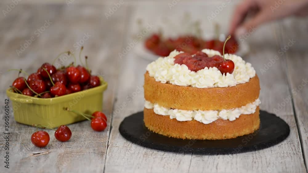 Young female confectioner decorating naked cherry cake. Young female confectioner decorating naked cherry cake.