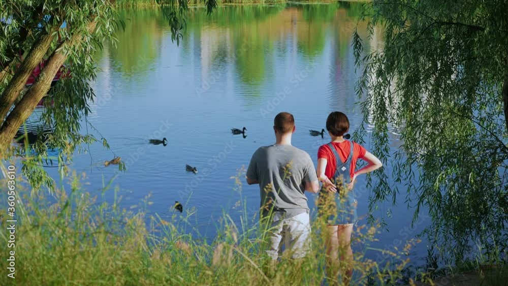 couple near the lake feeds wild ducks in the city park. Kyiv, Lake Poznyaki couple near the lake feeds wild ducks in the city park. Kyiv, Lake Poznyaki