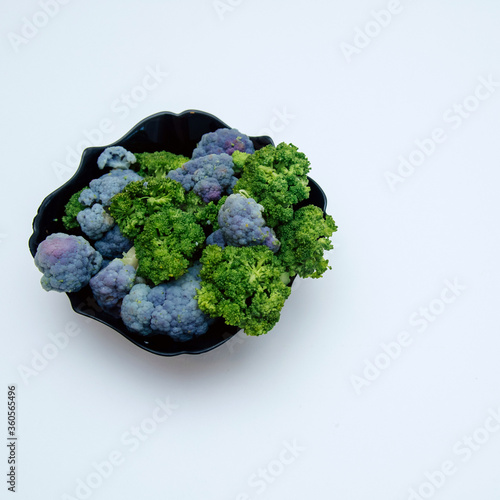 cauliflower lies in a black plate isolated on a white background.
