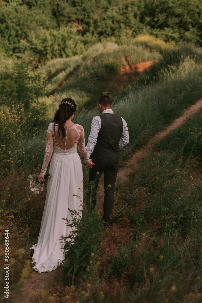 Bride and groom walking through the park