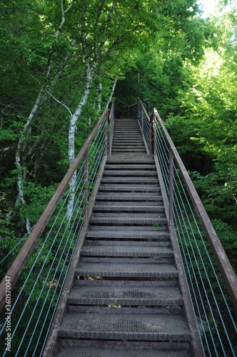 Metal staircase with railing on the green slope of the mountain leading up