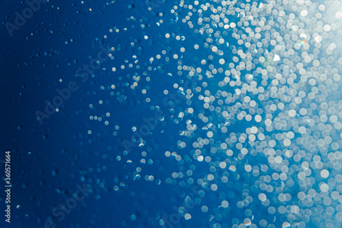 Blurred water drops on sky background, bokeh on blue background.