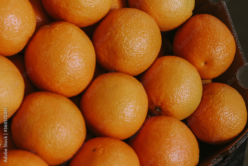 Juicy oranges in a cardboard box on market. Orange wallpaper. Yellow background. Juicy oranges in a cardboard box on market. Orange wallpaper. Yellow background.