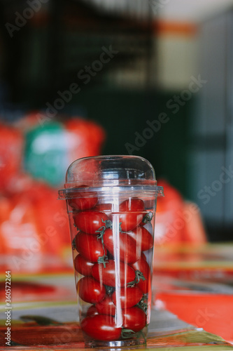 Plastic cup with cherry tomatoes against the background of bazaar.