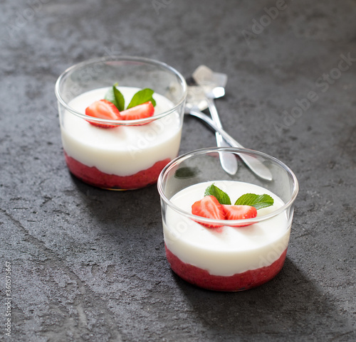 Panna cotta vanilla with strawberries in a glass Cup on a dark background