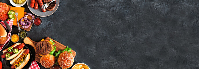 Summer BBQ food corner border with hot dog and hamburger buffet. Top down view over a dark slate banner background. Copy space.