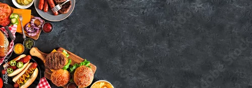 Obraz  z motywem Summer BBQ food corner border with hot dog and hamburger buffet. Top down view over a dark slate banner background. Copy space.