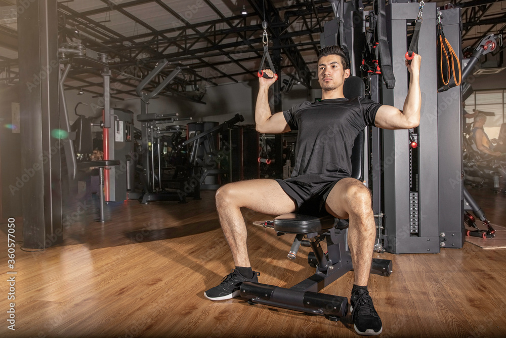 Fit man exercising workout with weights machine for arms in the gym Fit man exercising workout with weights machine for arms in the gym