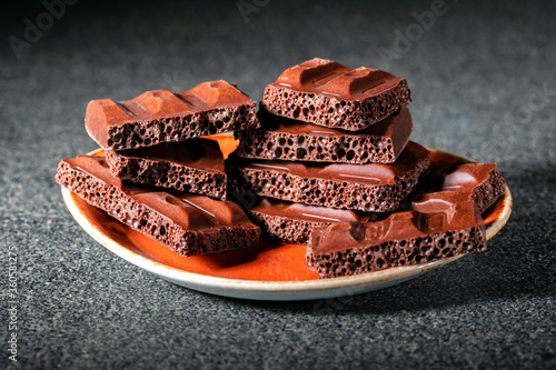 chocolate pieces in plate on gray surface.