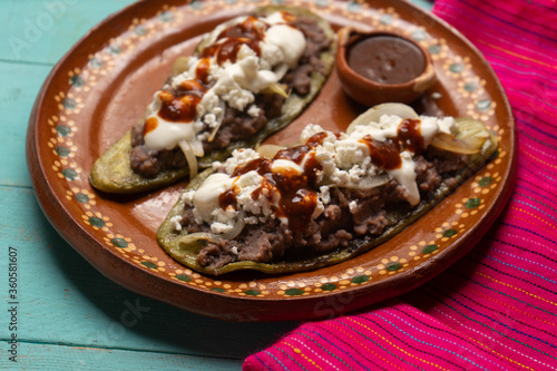 Mexican nopal cactus huaraches with cheese and beans on turquoise background