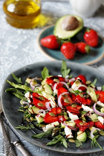 salad with strawberries and avocado, arugula, feta cheese, pumpkin seeds, red onion. dressed with balsamic sauce