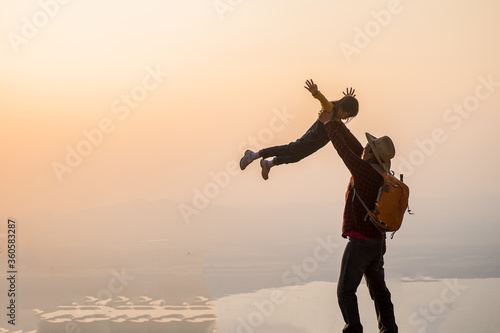 Man and girl standing on a mountain sunset in Thailand.
