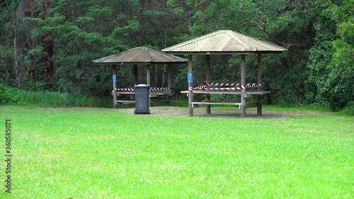 A picknic area on a clearing of a forest with wooden tables and a shed closed due to covid-19 restrictions. Warning tabels block the entrance. photo