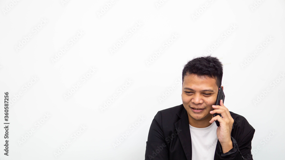 A portrait of happy young Asian businessman smiling while having conversation on the phone with isolated white background. Career business job concept. A portrait of happy young Asian businessman smiling while having conversation on the phone with isolated white background. Career business job concept.