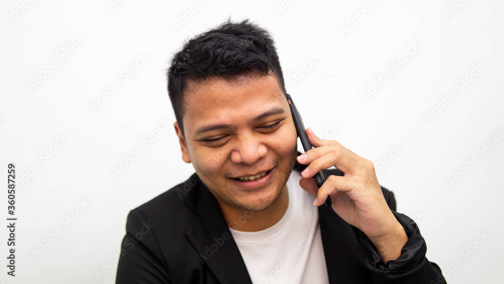 A portrait of happy young Asian businessman smiling while having conversation on the phone with isolated white background. Career business job concept. A portrait of happy young Asian businessman smiling while having conversation on the phone with isolated white background. Career business job concept.