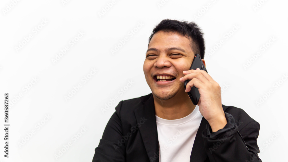 A portrait of happy young Asian businessman laughing while talking and having conversation on the phone with isolated white background. Career business job concept. A portrait of happy young Asian businessman laughing while talking and having conversation on the phone with isolated white background. Career business job concept.