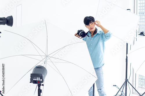 young photographer is taking pictures in the studio with a digital camera.