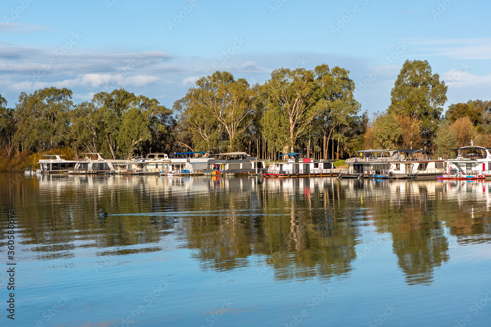 The reflection of house boats and tree on a calm river murray located in the river land at Berri South Australia on 20th June 2020