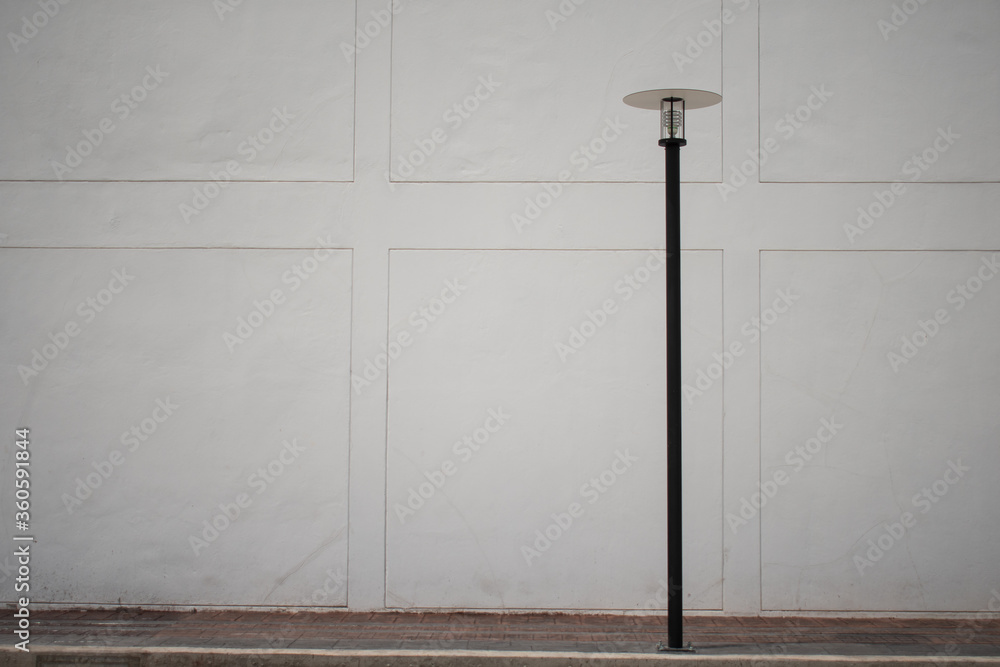 white concrete wall and street floor lamp pole