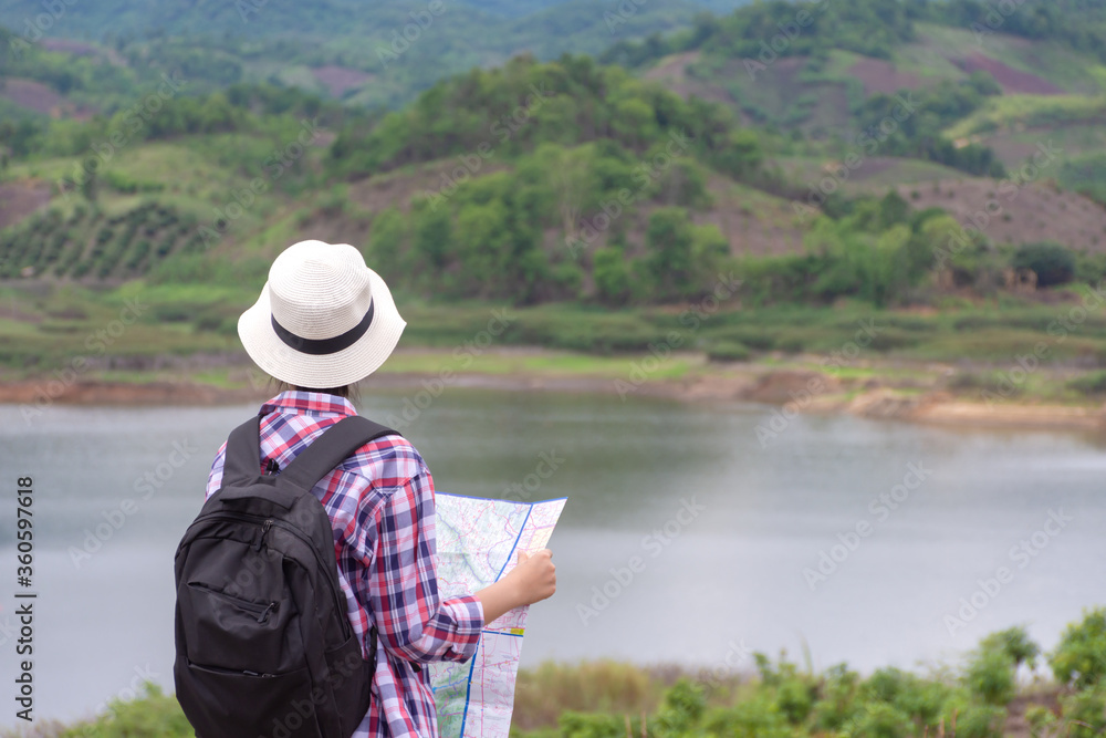 woman traveling with backpacker holding map looking at mountain and lake woman traveling with backpacker holding map looking at mountain and lake