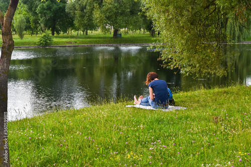 A lonely young woman is sitting on the beach and reading a book.