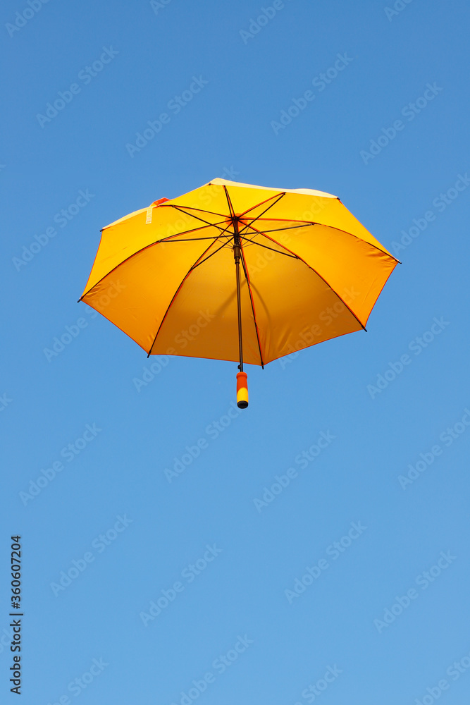 Orange colored umbrella against a clear blue sky