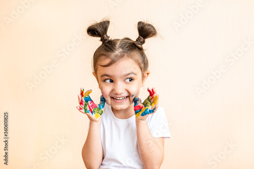 Happy little girl with painted hands. the child joyfully shows his palms painted with paints. painted children's palms