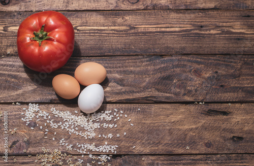 Cuban rice ingredients: tomato, rice and eggs on a wooden background