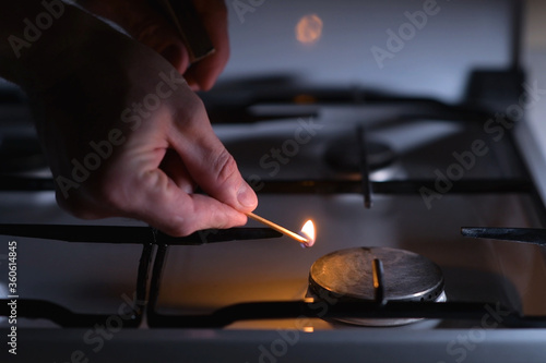 A man going to light a gas stove with a match