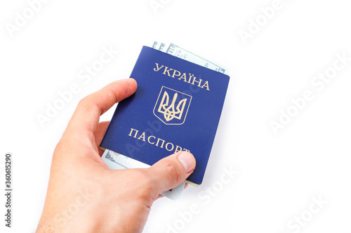 Ukrainian passport on a white background. Dollars of 100 dollars are inside the passport at different angles. Male hand holds, gives a passport with dollars inside