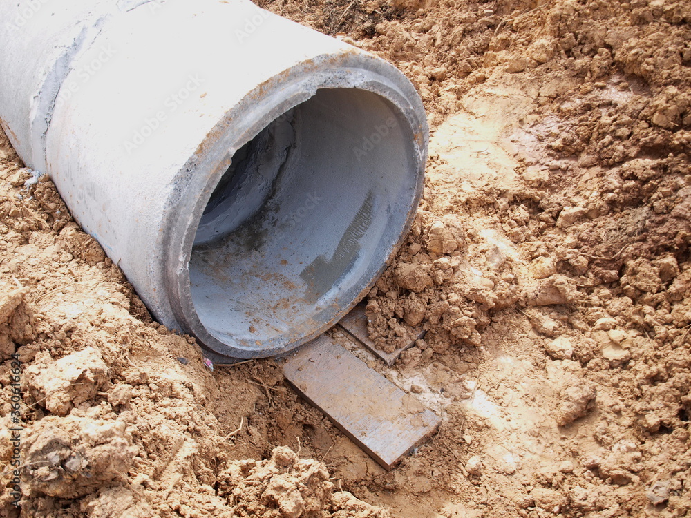 Slabs supporting drains in the ground. On the ground background in the construction of a water side drainage system. Selective focus Slabs supporting drains in the ground. On the ground background in the construction of a water side drainage system. Selective focus