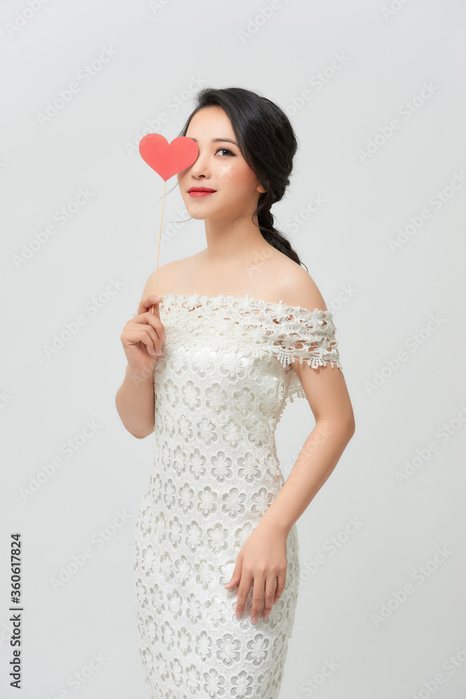 Studio portraits with beautiful bride isolated on white background. She is holding red heart. Studio portraits with beautiful bride isolated on white background. She is holding red heart.