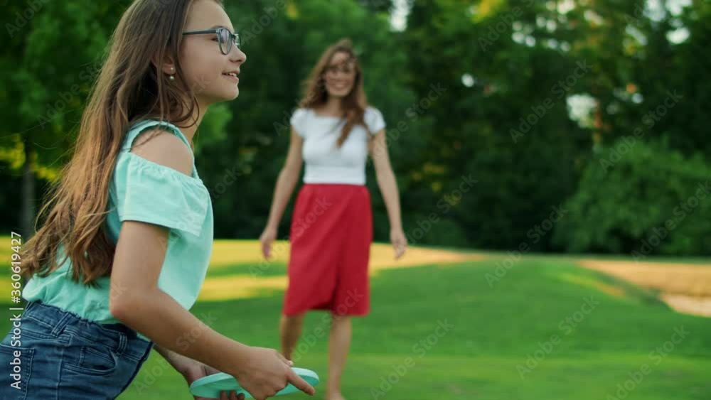 Woman throwing frisbee disk to daughter in park. Girl catching frisbee plate Woman throwing frisbee disk to daughter in park. Girl catching frisbee plate
