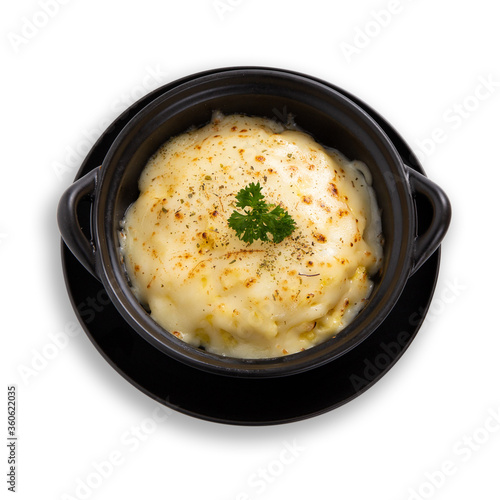 Baked potato with cheese on black plate on white background.
