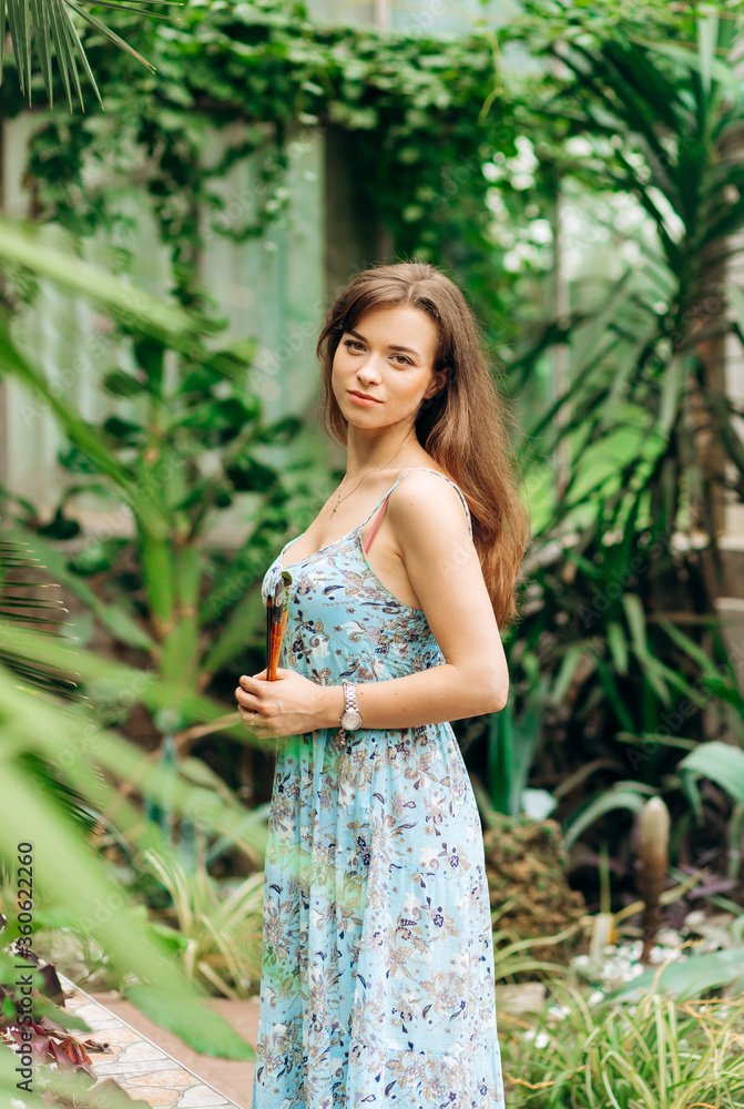 Portrait of a young artist in a blue dress with brushes in her hands. Botanical Garden. Portrait of a young artist in a blue dress with brushes in her hands. Botanical Garden.