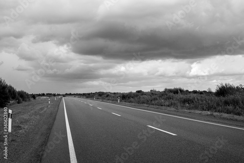 Highway going to the horizon. Beautiful thunderclouds. Black and white photo. Auto travel.