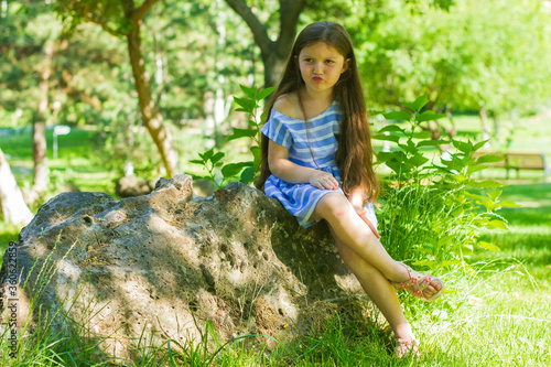 a little girl sitting on a stone in park