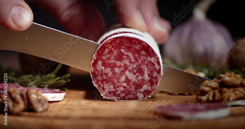 Stick of salami cut into pieces with walnuts and rosemary.