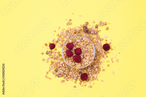 Crispy muesli with raspberry dry Breakfast isolated on yellow background selective focus, top view