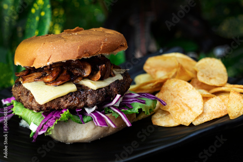 beef burger with chips on a black plate dark background 