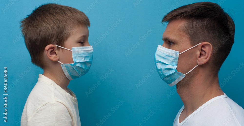 Father and son wearing protective medical mask looking to each other.