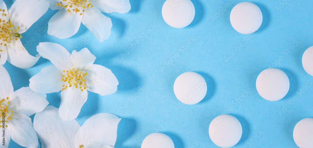 Medical background with white capsules. on a blue background. with jasmine flowers. Depression antidepressants. Women's health. Medical background with white capsules. on a blue background. with jasmine flowers. Depression antidepressants. Women's health.