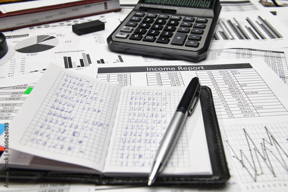 Obraz premium Top view of office employee's desk - work with financial reports, analysis and accounting, tables and graphs, various office items for bookkeeping