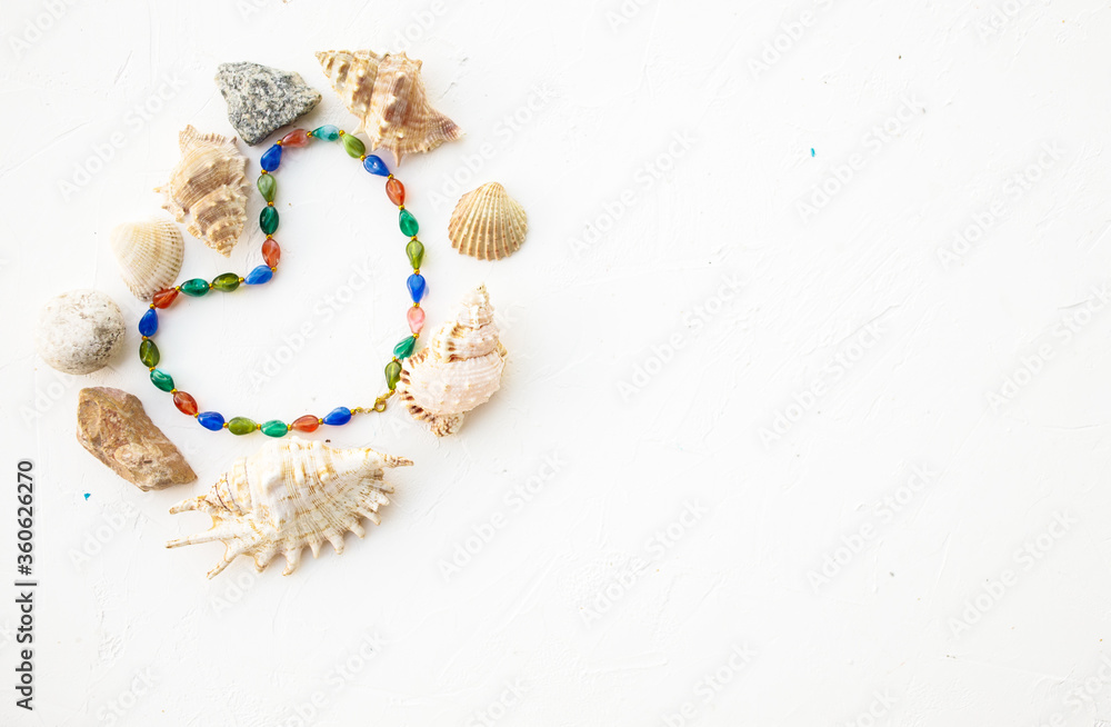Set of seashells, pearls and stones in form heart on a white background. Place for inscription. Postcard. Set of seashells, pearls and stones in form heart on a white background. Place for inscription. Postcard.