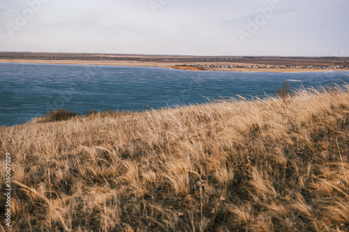  View from a hill with dry grass to a frozen lake without snow