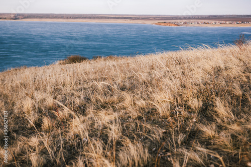  View from a hill with dry grass to a frozen lake without snow